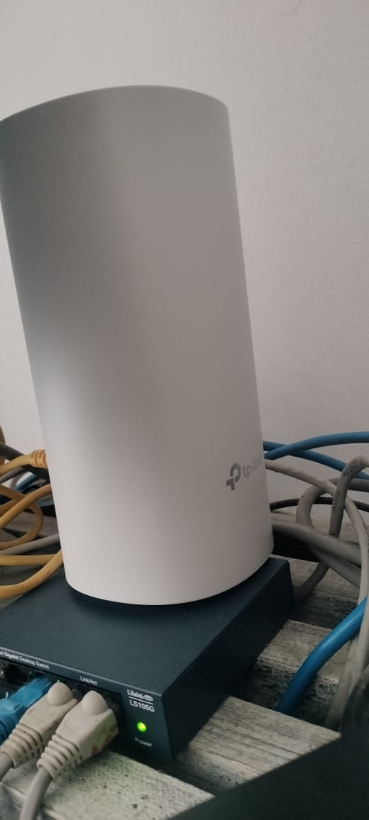 A Deco E4 unit wired into a five-port gigabit switch for ethernet backhaul