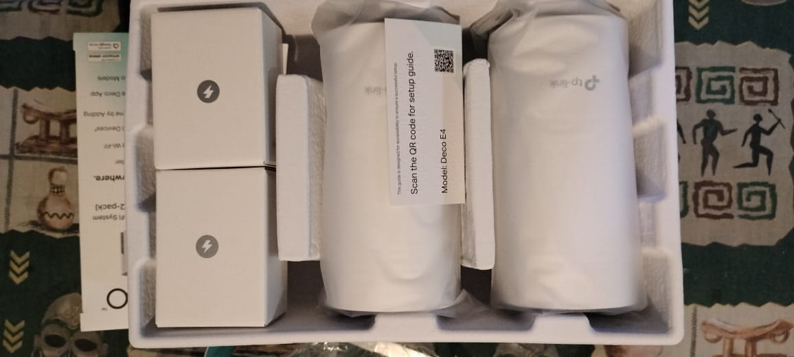 The Deco E4 two-pack unboxed, showing both units, two power adapters and the setup guide