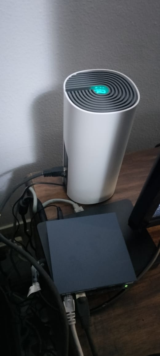 A TP-Link Deco E4 unit with a solid green light, connected and running on a fibre network