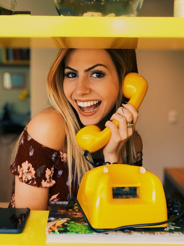 A woman using an old yellow telephone